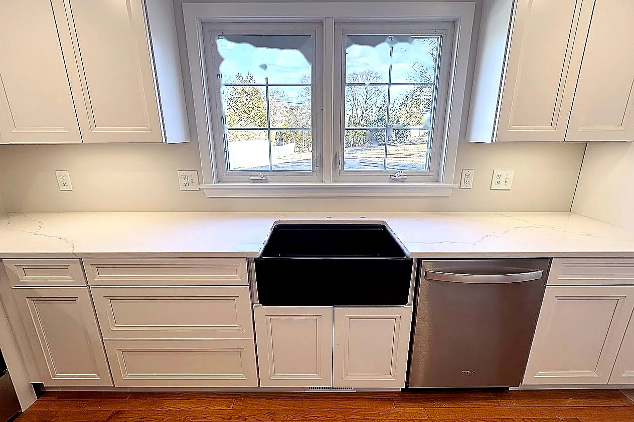White countertop fitted around a black farmhouse sink by Dream Stoneworks